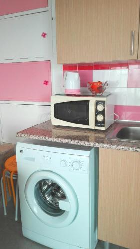 a microwave sitting on top of a washing machine in a kitchen at Lisbon Coast Flat in Quinta de Santo António