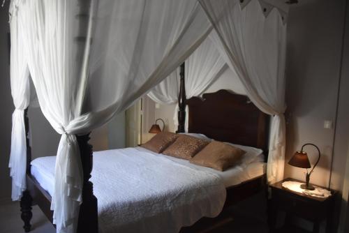 a bedroom with a canopy bed with white curtains at Gite d'Arles "Villa Doudou" in Le Moule