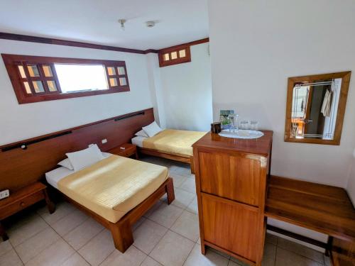 a small room with two beds and a mirror at Hostal Macaw in Guayaquil