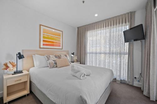 a bedroom with a large bed and a window at Belle Escapes - Beachside Apartment in Glenelg in Glenelg