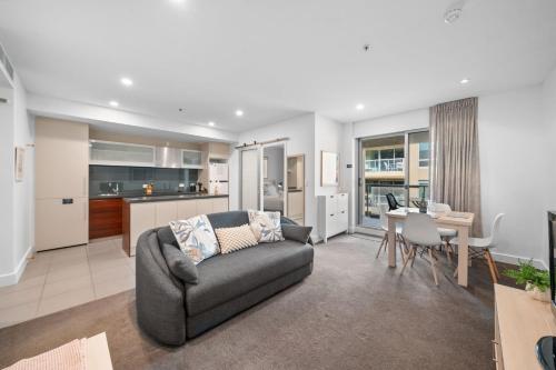 a living room with a couch and a kitchen at Belle Escapes - Beachside Apartment in Glenelg in Glenelg