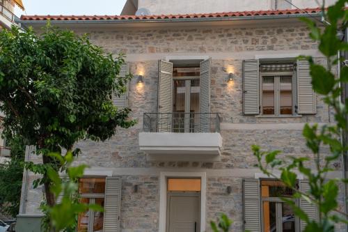a stone house with a balcony and shutters at Nest in the City Residence in Volos