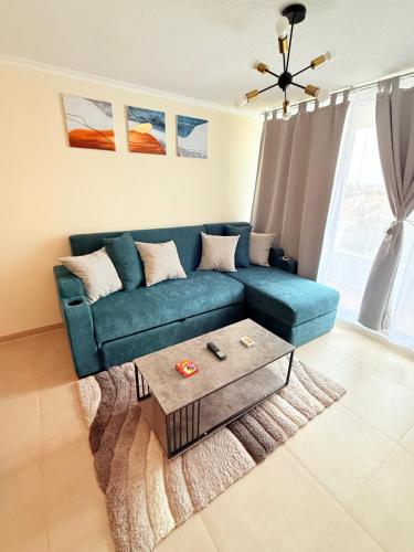 a living room with a blue couch and a coffee table at Departamento con piscina a pasos de la playa en La Serena in La Serena