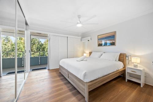 a white bedroom with a bed and windows at Stylish 4-Bed Townhouse with Panoramic Ocean Views in Brisbane