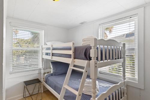 Only Steps 2 Ocean Couples Beach Retreat في فولي بيتش: سرير بطابقين في غرفة صغيرة بها نوافذ