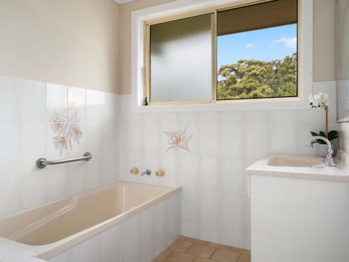 Un baño blanco con bañera y ventana. en Toormina Retreat, en Toormina