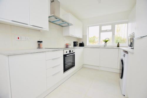 a white kitchen with white cabinets and appliances at Spacious Central Oxford Detached Home in Oxford