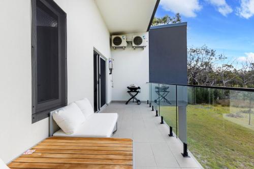 a balcony with white furniture and a large window at Modern 2 Bed Apartment with BBQ - 6 Min walk to beach in Callala Beach
