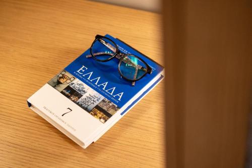 a book with a pair of glasses sitting on top of it at Nest in the City Residence in Volos