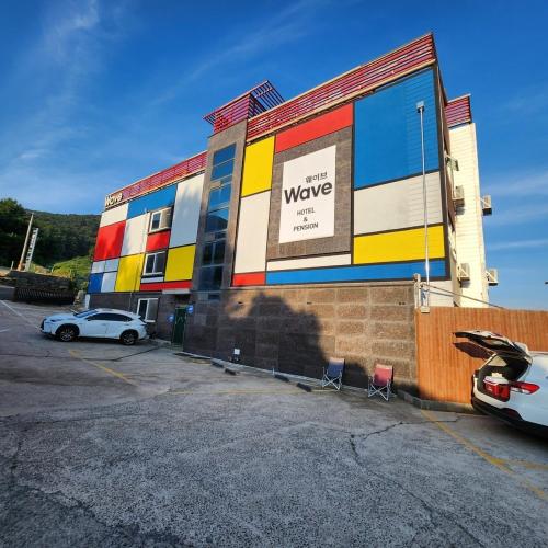 a colorful building with a car parked in a parking lot at Geoje Wave Hotel & Pension in Geoje