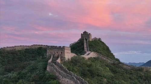 a castle on top of a hill with a cloudy sky at 隐谷私院The Great Wall Valley in Gubeikou