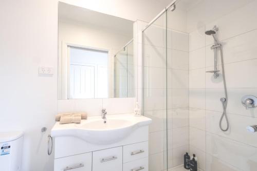 une salle de bain blanche avec un lavabo et une douche dans l'établissement Little Tawny Studio - Private One Bedroom In Rye, à Rye