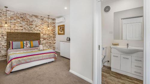 - une chambre avec un mur en briques, un lit et un lavabo dans l'établissement Little Tawny Studio - Private One Bedroom In Rye, à Rye