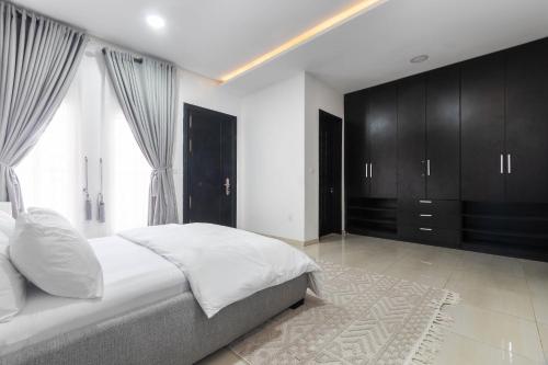 a bedroom with a white bed and black cabinets at Spacious 4 bed - Fast Internet - Free Parking - Swimming Pool in Lagos