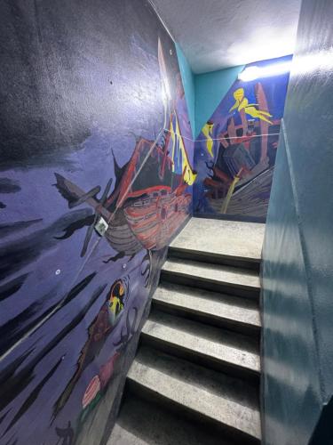 a staircase with a mural of a boat on the wall at Essaouira trip hostel in Essaouira