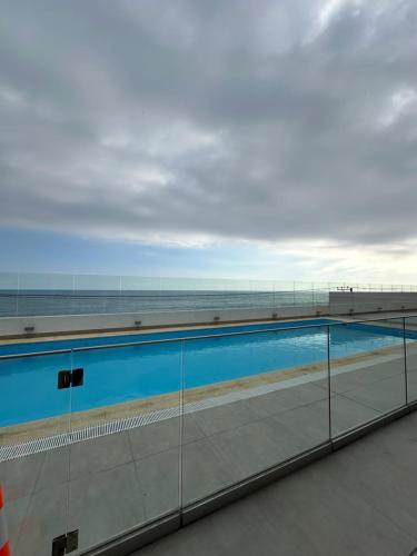 a swimming pool with the ocean in the background at Depto privado con vista despejada al mar en 1 línea, terraza 20 mts y estacionamiento con acceso desde el borde costero in Vina del Mar