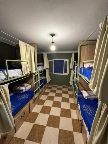 a room with three bunk beds and a checkered floor at Essaouira trip hostel in Essaouira