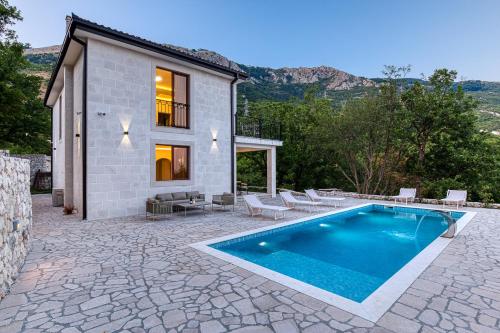 a villa with a swimming pool in front of a house at Villa 53 in Lapčići
