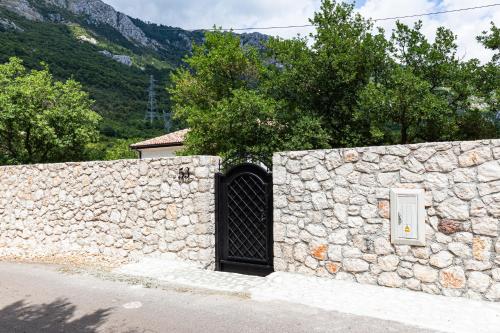 a gate in a stone wall with a door at Villa 53 in Lapčići