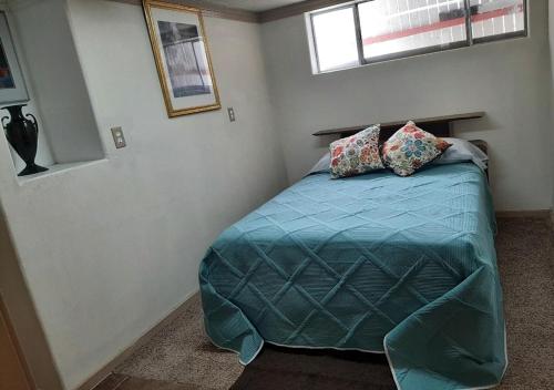 a bedroom with a bed with a blue comforter and two pillows at VIGILANTE INN Invincible Quarters in Tombstone
