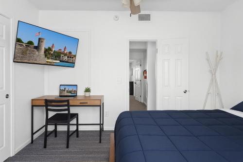 a bedroom with a bed and a desk with a laptop at Walk to Downtown - 3BR with Hot Tub & Games in St. Augustine