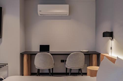 a room with a desk with two chairs and a laptop at Seissta Medellín in Medellín