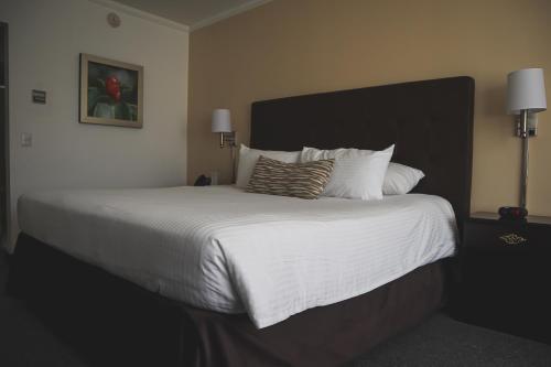 a bedroom with a large bed with white sheets and pillows at Taormina Hotel y Casino in San José