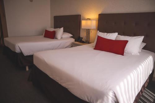 a hotel room with two beds with red pillows at Taormina Hotel y Casino in San José