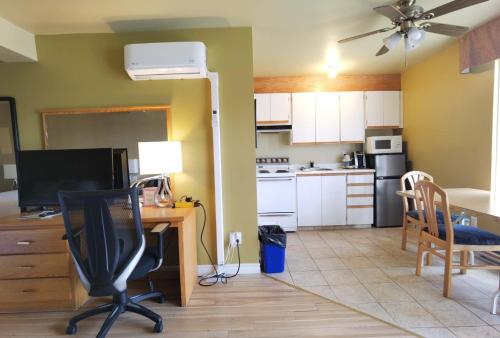 a kitchen with a table and a desk with a computer at Motel Grand-Pré Inc in Bonaventure
