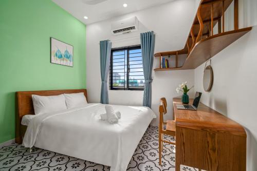a bedroom with a white bed and a wooden desk at Indochine House - Near My Khe Beach & City Center by The Key in Da Nang