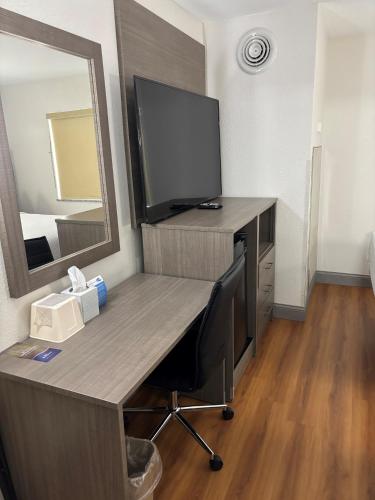 a desk with a television and a mirror in a room at Baymont by Wyndham Kingdom City in Kingdom City