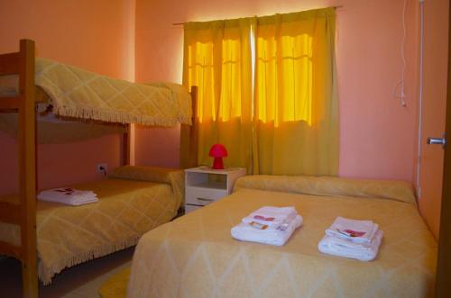 two beds in a bedroom with yellow curtains at Hospedaje Martina in Belén