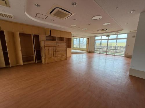 an empty room with wood floors and windows at ハイ沖縄金武店トイレお風呂共用 プレオープン中駐車場有 ペット同伴可能長期滞在可能2025年10月より車貸し出しサービス有希望であればお申し付けください in Kin
