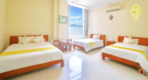 a bedroom with two beds and a large window at Hoang Yen Canary Hotel in Quy Nhon