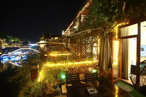 a house with lights on the side of it at night at Shuiyun Zhijian Homestay in Fenghuang