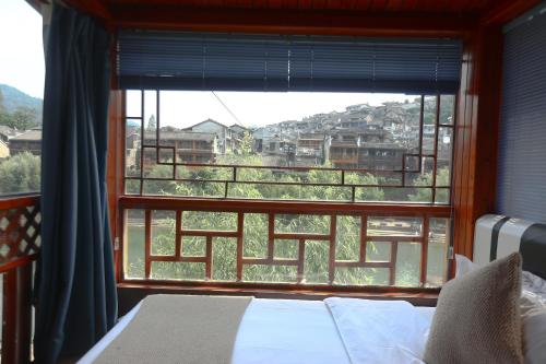 a bedroom with a large window with a view at Shuiyun Zhijian Homestay in Fenghuang