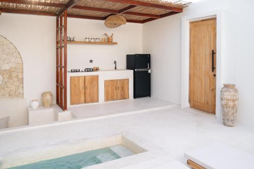 a white kitchen with a black refrigerator and a table at Kasih 2 - Villa with private pool in Gili T in Mantaak