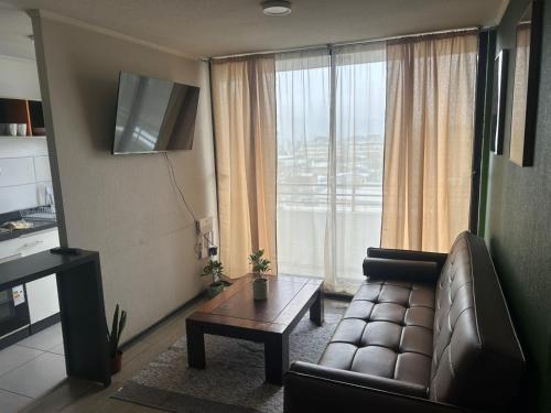a living room with a couch and a table and a window at Amplio departamento céntrico in Concepción