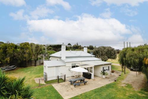 a white house with a picnic table in the yard at Clifftop Cottage at The Portsea Camp in Portsea