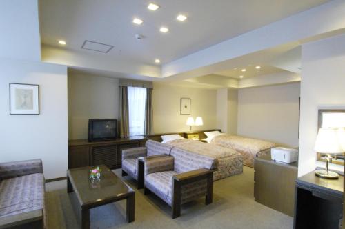a hotel room with a bed and a couch and a tv at Karuizawakurabu Hotel 1130 Hewitt Resort in Tsumagoi