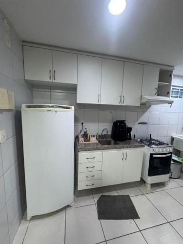 a kitchen with white cabinets and a white refrigerator at APARTAMENT BEACH FORTALEZA in Fortaleza
