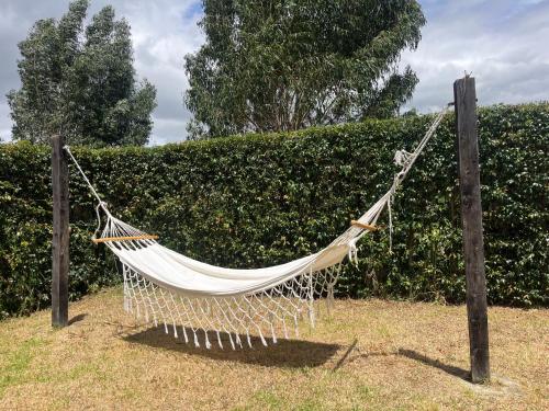 a hammock hanging from two poles in front of a hedge at Cabaña Campestre El Refugio in Paipa