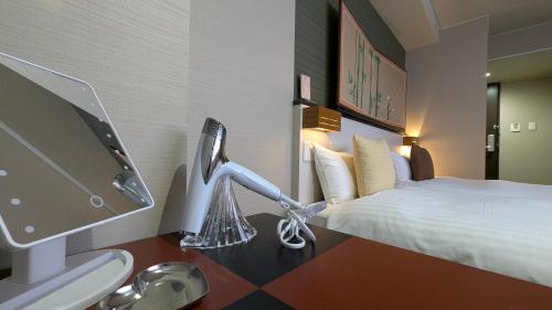 a hotel room with a bed and a desk with a lamp at Kyoto Inn Gion in Kyoto