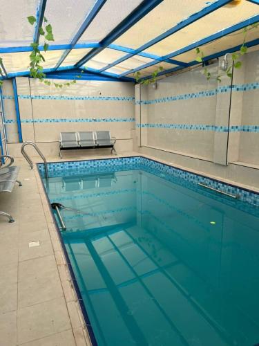 a large swimming pool with two benches in it at كمباوند شاليهات فابيلوس 