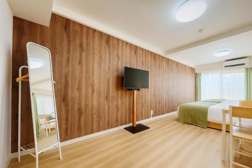 a bedroom with a bed and a tv on a wall at TOEI BUSSAN Building20 in Osaka