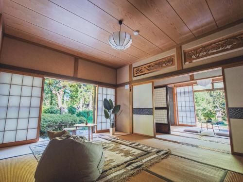 a living room with wooden ceilings and large windows at 佐渡古民家一棟貸切 Active Art Hotel 日本庭園 佐渡アート in Sado