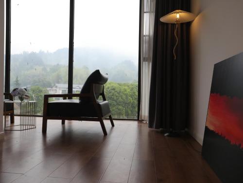 a living room with a chair and a large window at Zhangjiajie Southgate Flower Garden Lodge at the Park Entrance in Zhangjiajie
