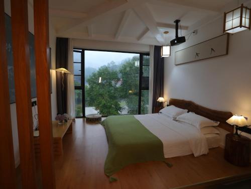 a bedroom with a large bed and a large window at Zhangjiajie Southgate Flower Garden Lodge at the Park Entrance in Zhangjiajie