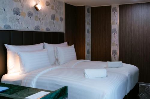 a large bed with white pillows in a room at วัน บัดเจท เชียงราย บ้านใหม่ in Chiang Rai