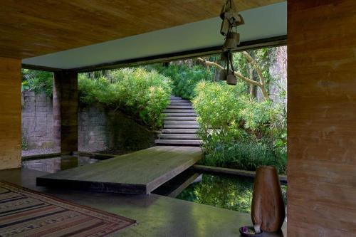 a room with a bridge over a pond with a stairway at Chameleon Villa Bali in Tabanan
